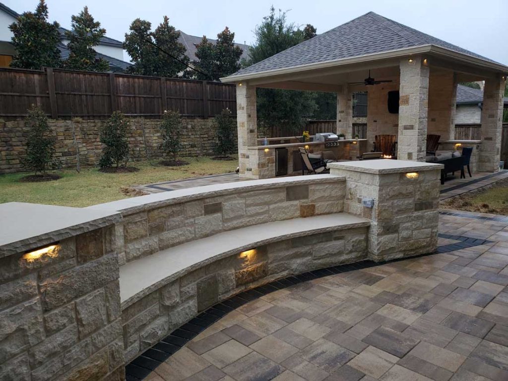 A stone wall with lights on it and a gazebo in the background.